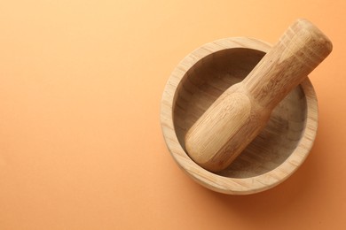 Photo of Wooden mortar and pestle on light brown background, top view. Space for text