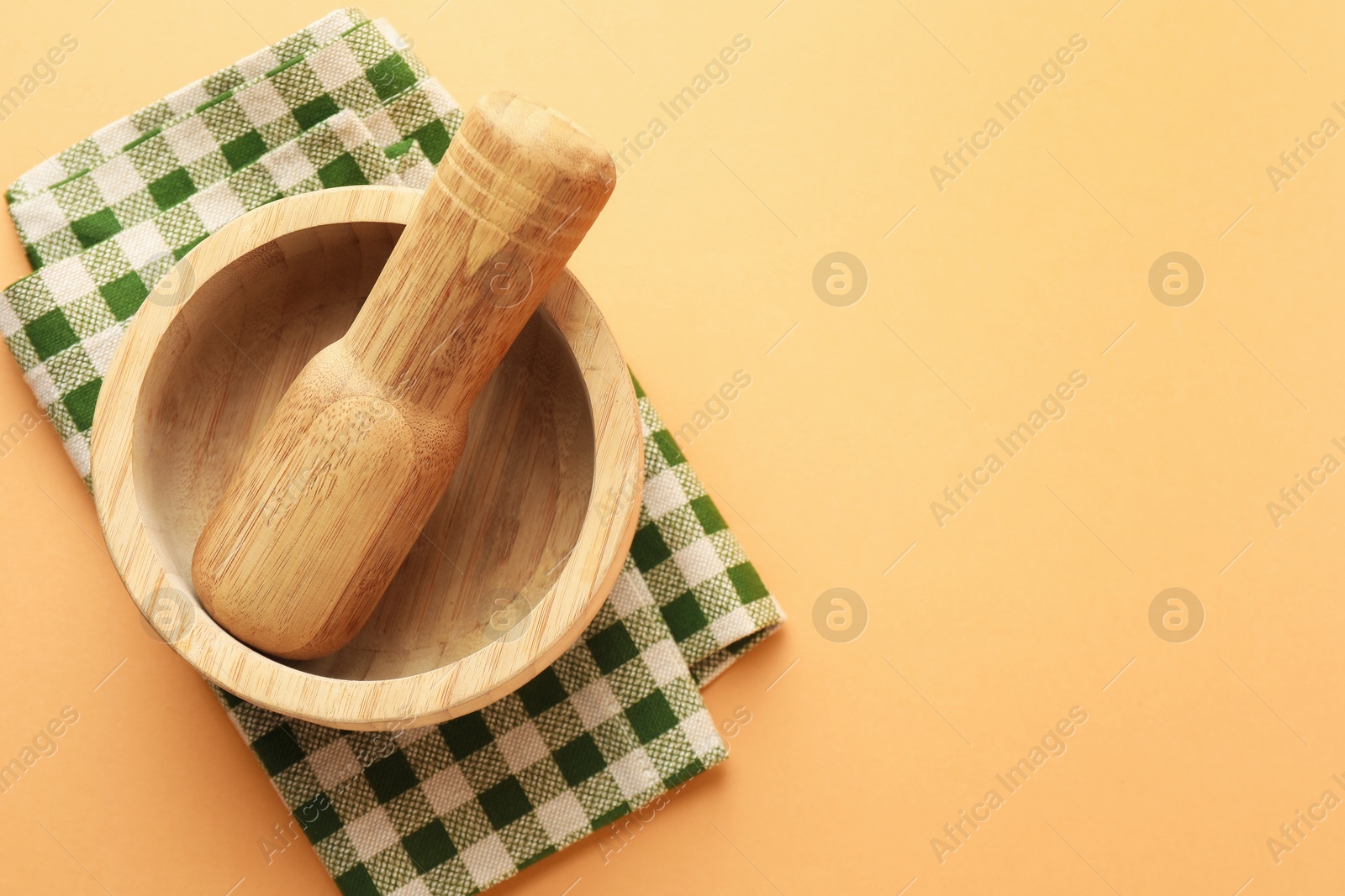 Wooden mortar, pestle and cloth on light brown background, top view. Space for text Photo of Wooden mortar, pestle and cloth on light brown background, top view. Space for text