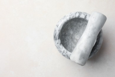 Photo of Marble mortar and pestle on white table, top view. Space for text
