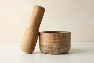 Photo of Wooden mortar and pestle on white table, closeup