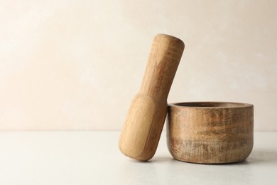 Photo of Wooden mortar and pestle on white table, closeup. Space for text
