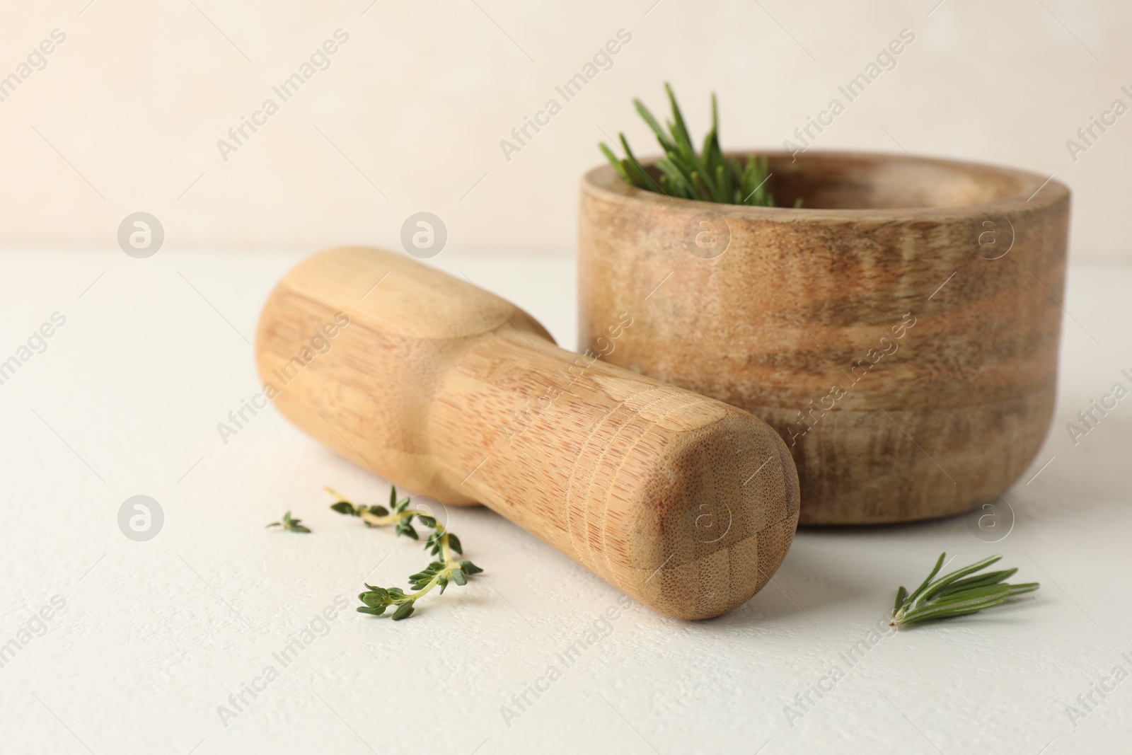 Wooden mortar with rosemary, thyme and pestle on white table, closeup Photo of Wooden mortar with rosemary, thyme and pestle on white table, closeup