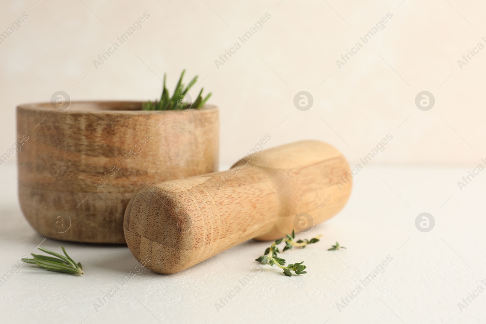 Wooden mortar with rosemary, thyme and pestle on white table, closeup Photo of Wooden mortar with rosemary, thyme and pestle on white table, closeup