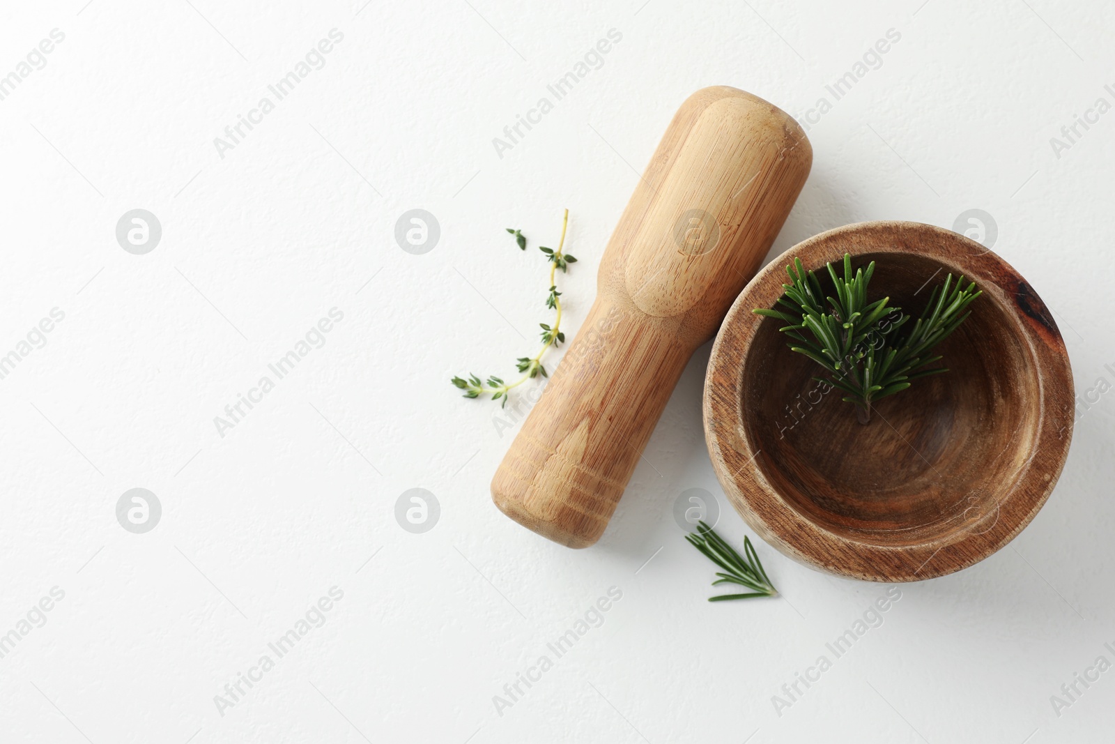 Wooden mortar with rosemary, thyme and pestle on white table, flat lay. Space for text Photo of Wooden mortar with rosemary, thyme and pestle on white table, flat lay. Space for text