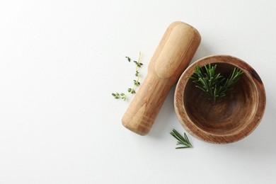 Photo of Wooden mortar with rosemary, thyme and pestle on white table, flat lay. Space for text