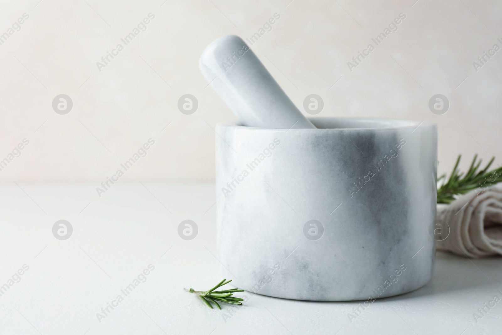 Marble mortar with rosemary and pestle on white table, closeup. Space for text Photo of Marble mortar with rosemary and pestle on white table, closeup. Space for text