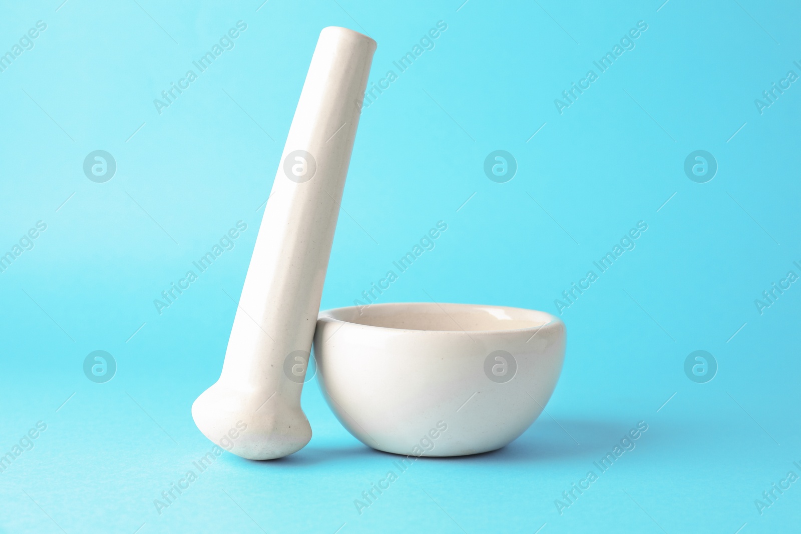 Ceramic mortar and pestle on light blue background, closeup Photo of Ceramic mortar and pestle on light blue background, closeup