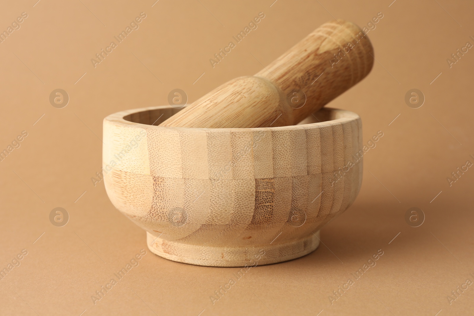 Wooden mortar and pestle on light brown background, closeup Photo of Wooden mortar and pestle on light brown background, closeup