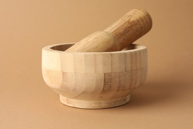 Photo of Wooden mortar and pestle on light brown background, closeup