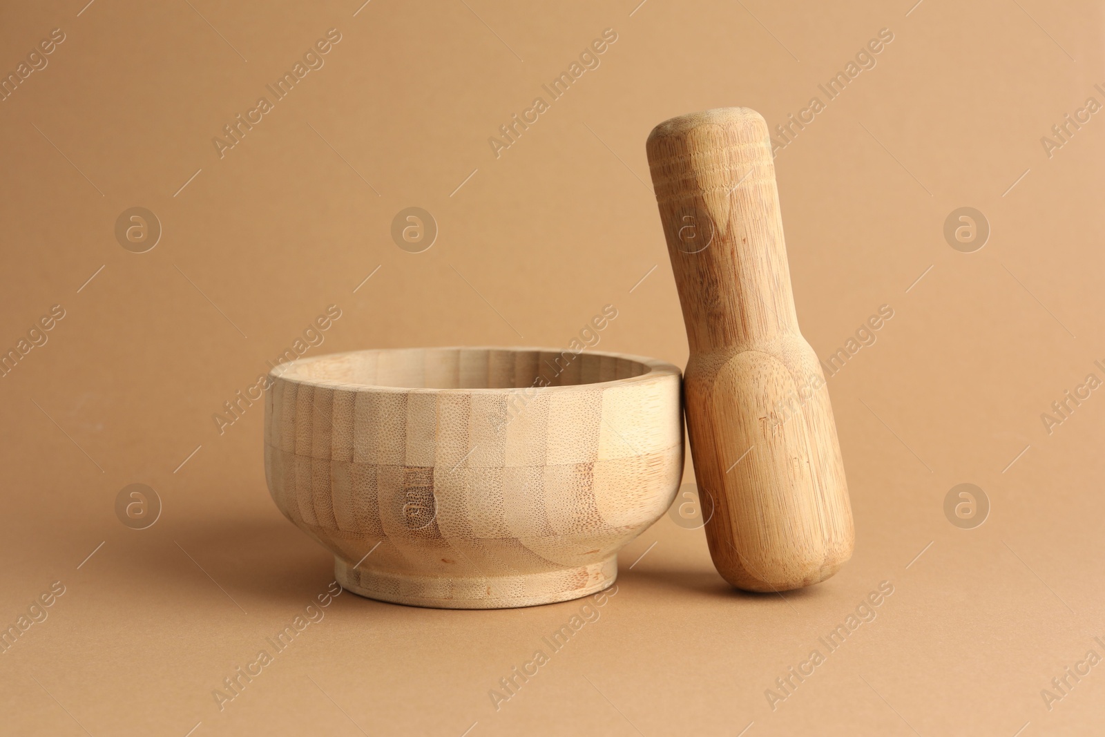 Wooden mortar and pestle on light brown background, closeup Photo of Wooden mortar and pestle on light brown background, closeup
