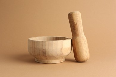 Photo of Wooden mortar and pestle on light brown background, closeup