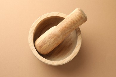 Photo of Wooden mortar and pestle on light brown background, top view