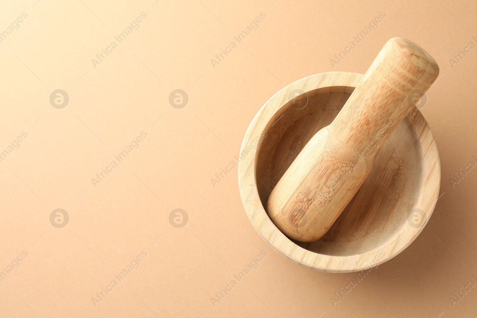 Wooden mortar and pestle on light brown background, top view Photo of Wooden mortar and pestle on light brown background, top view