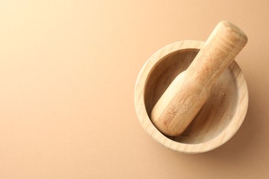 Photo of Wooden mortar and pestle on light brown background, top view