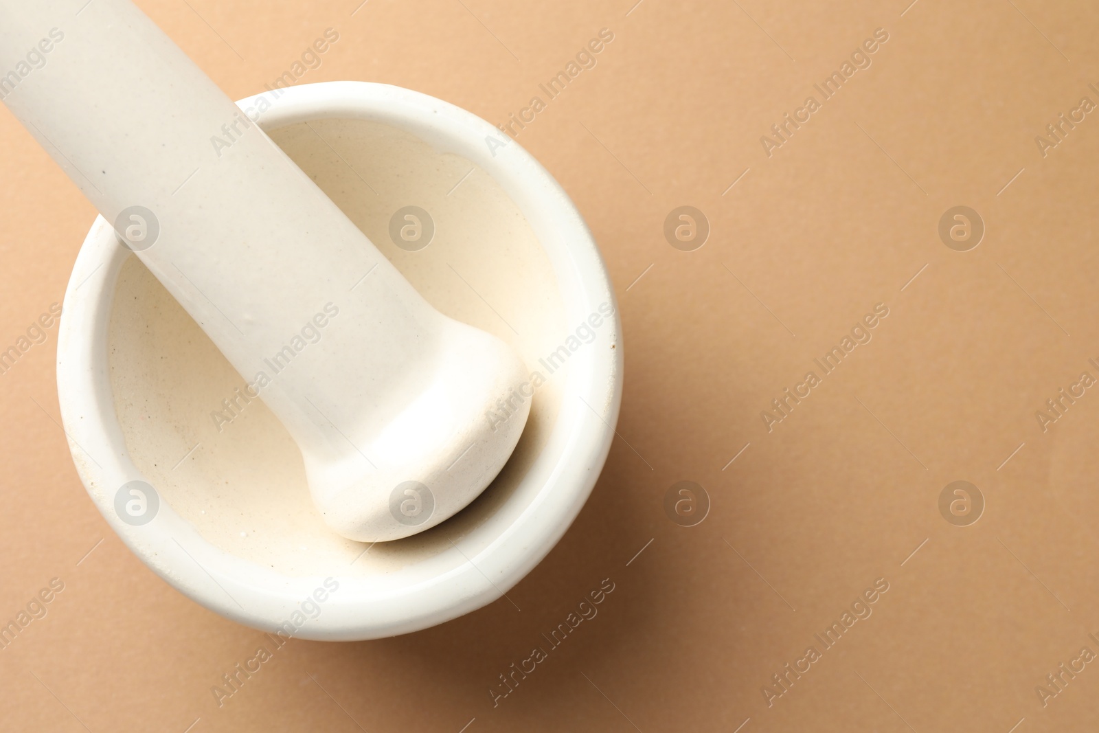 Ceramic mortar and pestle on light brown background, top view. Space for text Photo of Ceramic mortar and pestle on light brown background, top view. Space for text