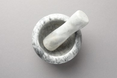 Photo of Marble mortar and pestle on light grey background, top view