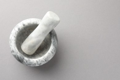 Photo of Marble mortar and pestle on light grey background, top view. Space for text