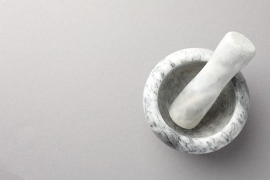 Photo of Marble mortar and pestle on light grey background, top view. Space for text