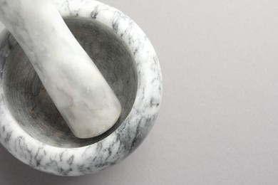 Photo of Marble mortar and pestle on light grey background, top view. Space for text