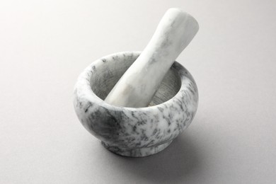 Photo of Marble mortar and pestle on light grey background, closeup