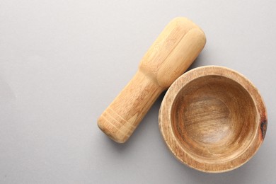 Photo of Wooden mortar and pestle on light grey background, top view. Space for text