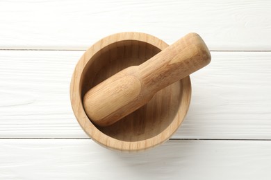 Photo of Mortar and pestle on white wooden table, top view