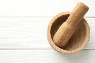 Photo of Mortar and pestle on white wooden table, top view. Space for text