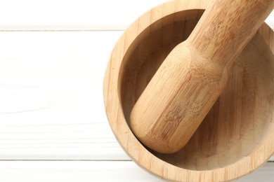 Photo of Mortar and pestle on white wooden table, top view. Space for text