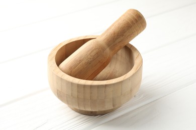Photo of Mortar and pestle on white wooden table, closeup