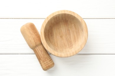 Photo of Mortar and pestle on white wooden table, top view