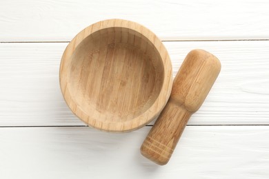 Photo of Mortar and pestle on white wooden table, top view