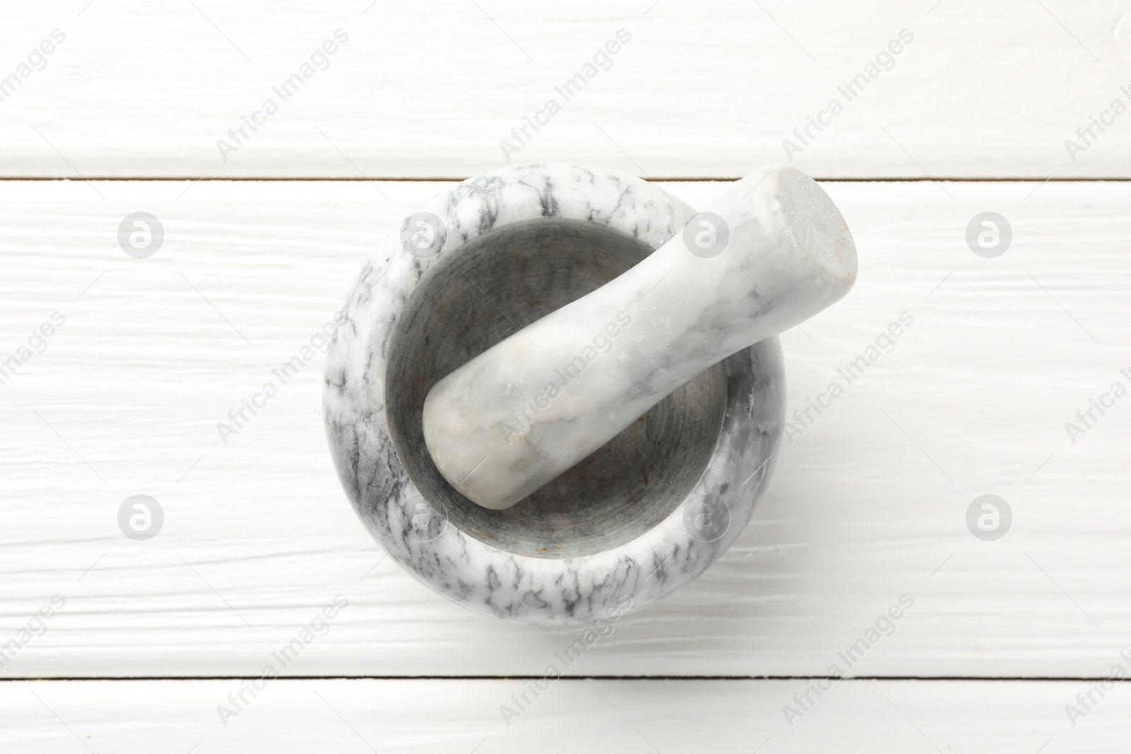 Marble mortar and pestle on white wooden table, top view Photo of Marble mortar and pestle on white wooden table, top view