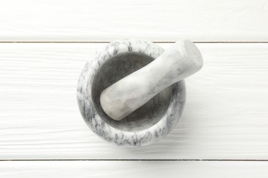 Photo of Marble mortar and pestle on white wooden table, top view