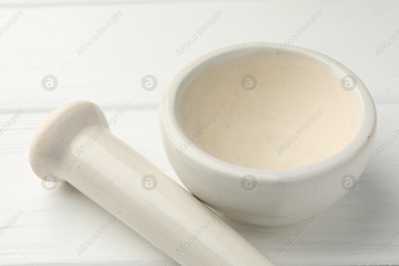 Ceramic mortar and pestle on white wooden table, closeup Photo of Ceramic mortar and pestle on white wooden table, closeup