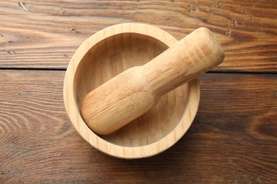 Photo of Mortar and pestle on wooden table, top view