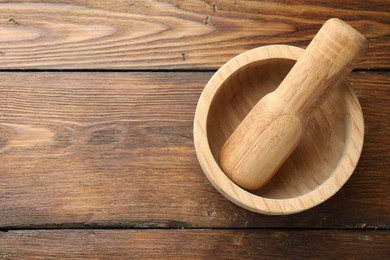 Photo of Mortar and pestle on wooden table, top view. Space for text