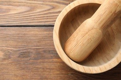 Photo of Mortar and pestle on wooden table, top view. Space for text