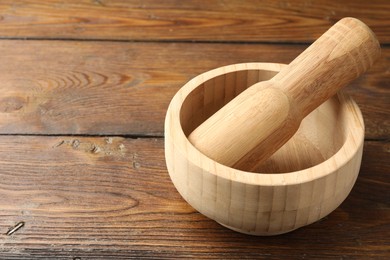 Photo of Mortar and pestle on wooden table, closeup. Space for text