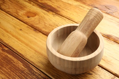 Photo of Mortar and pestle on wooden table, closeup. Space for text