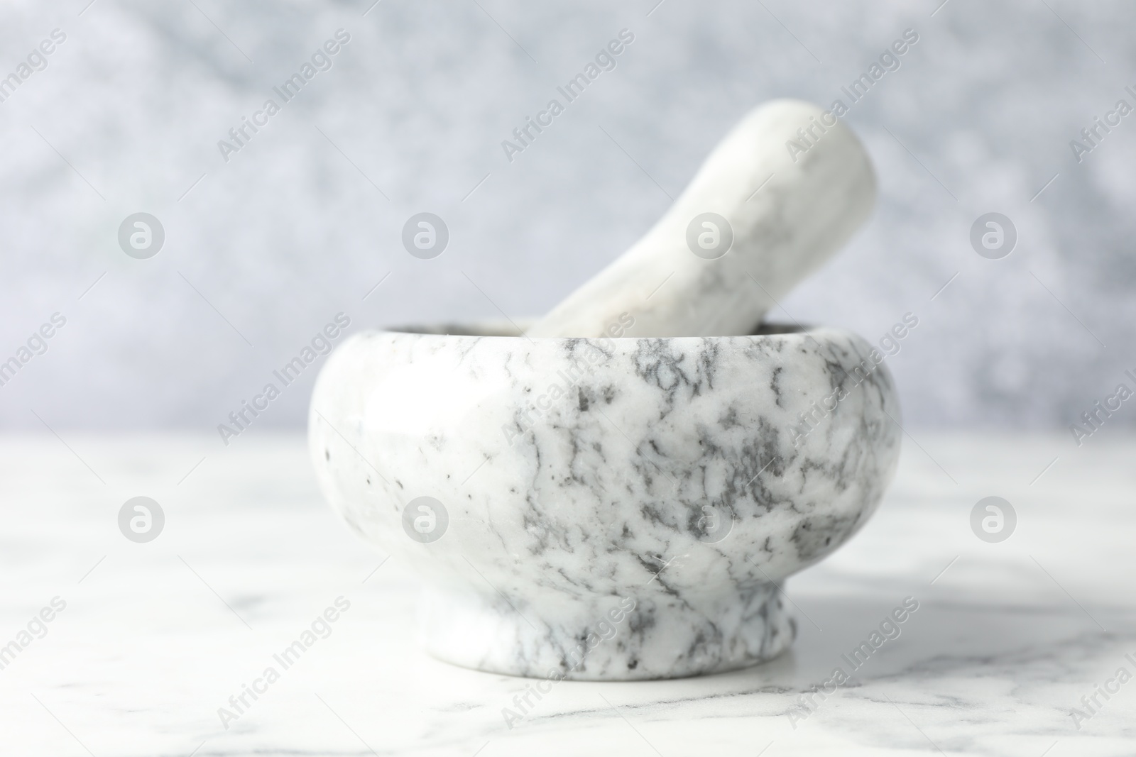 Mortar and pestle on white marble table, closeup Photo of Mortar and pestle on white marble table, closeup