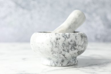 Photo of Mortar and pestle on white marble table, closeup