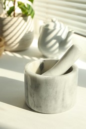 Photo of Marble mortar and pestle on windowsill indoors, closeup