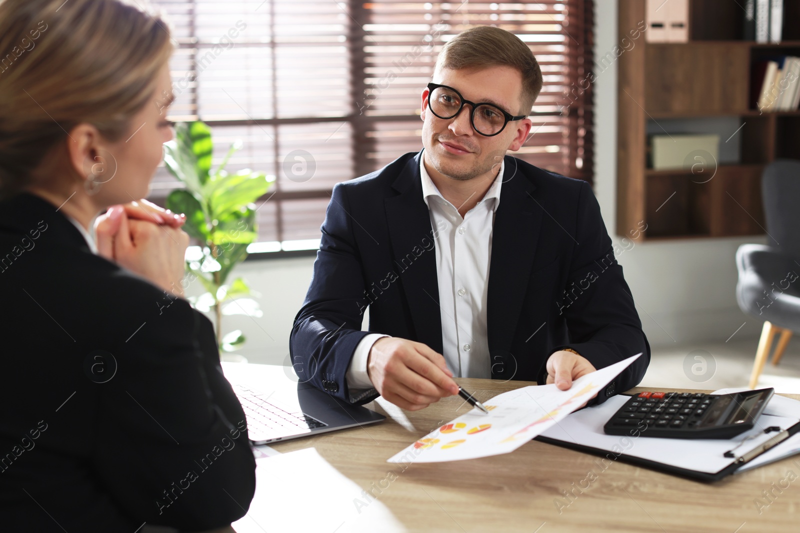 Woman having meeting with banker at desk in office Photo of Woman having meeting with banker at desk in office
