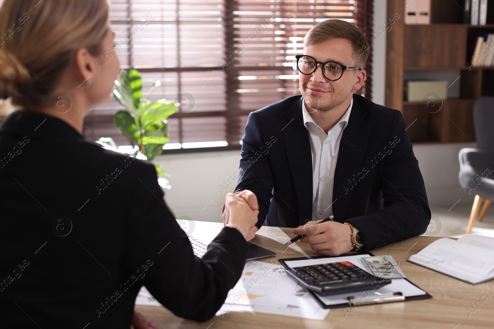 Woman shaking hands with banker during meeting in office Photo of Woman shaking hands with banker during meeting in office