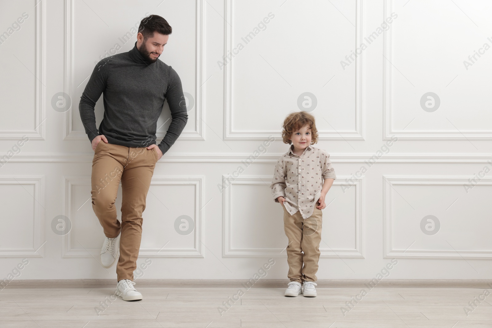 Photo of Happy father and his son near white wall indoors