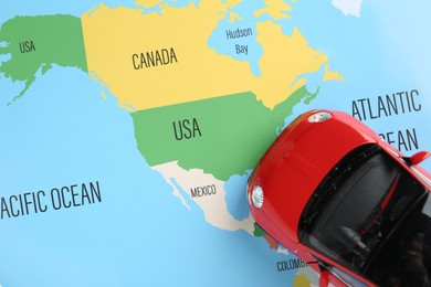Photo of Road trip concept. Toy car on world map, top view