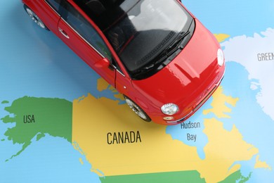 Photo of Road trip concept. Toy car on world map, above view