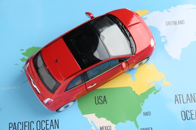Photo of Road trip concept. Toy car on world map, above view