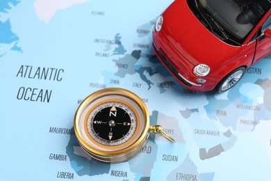 Photo of Road trip concept. Toy car and compass on world map, above view