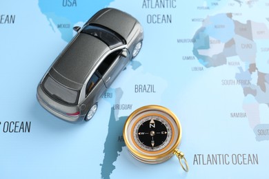 Photo of Road trip concept. Toy car and compass on world map, above view